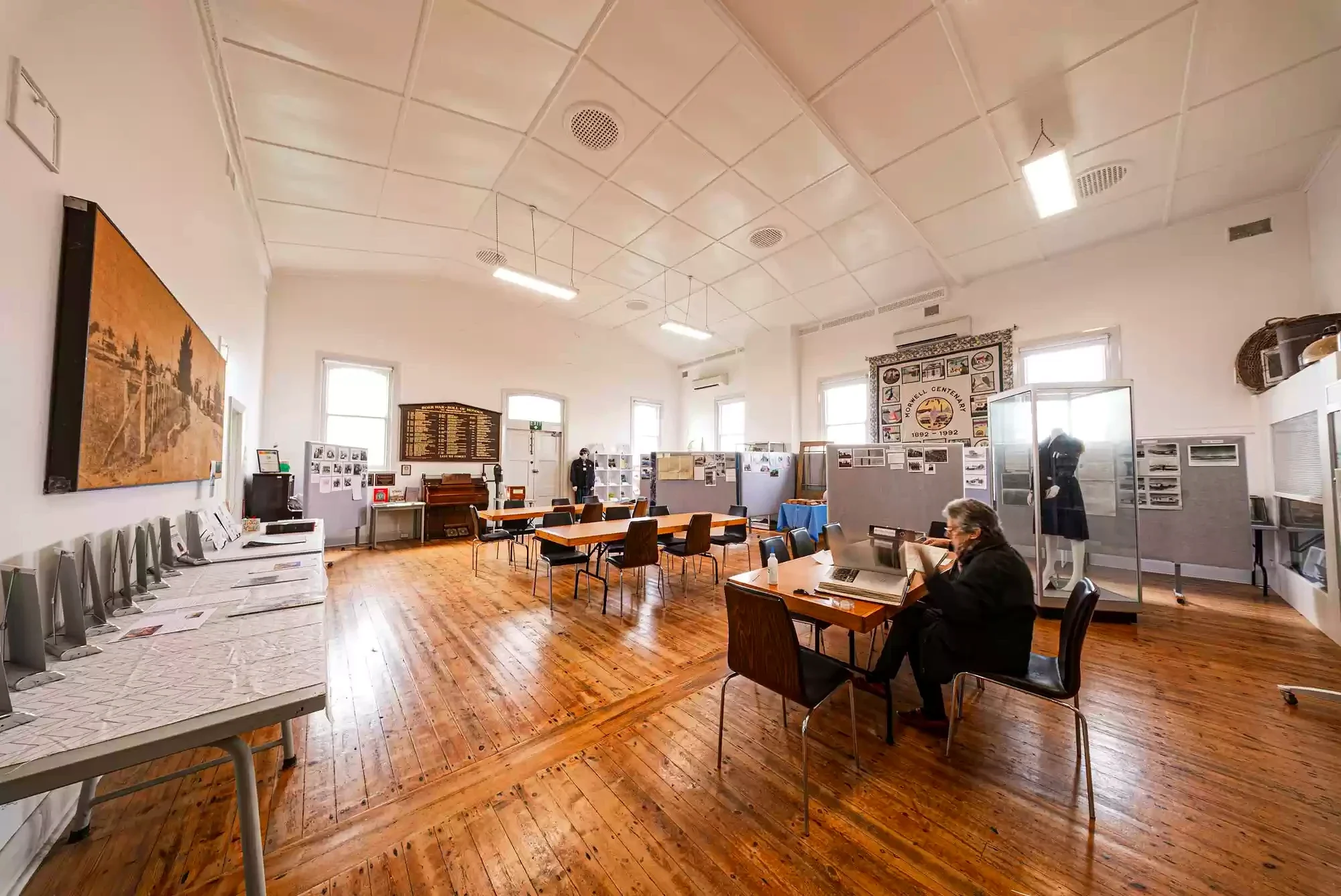 A researcher works among tables, photographs and display boards inside Morwell Historical Society.