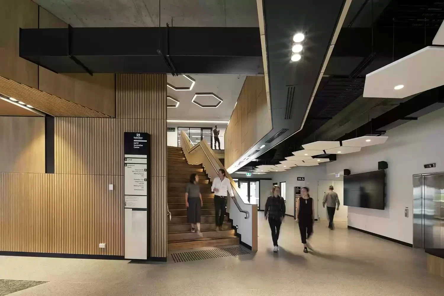 People cross a timber-lined circulation space inside Morwell Innovation Centre.