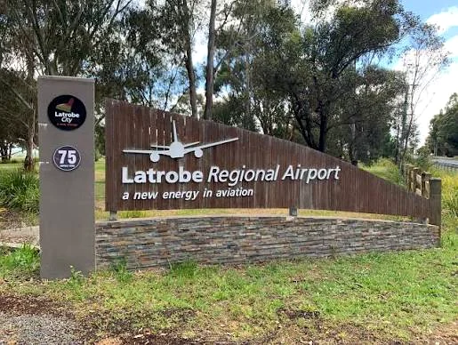 The timber and stone Latrobe Regional Airport entrance sign among trees.