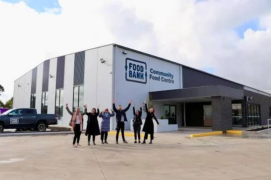 A group waving outside the Foodbank Community Food Centre building.