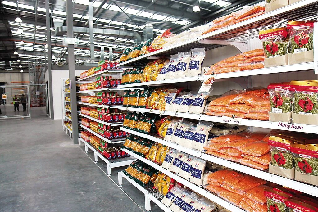 Shelves stocked with bags of dried food inside a warehouse-style supermarket.
