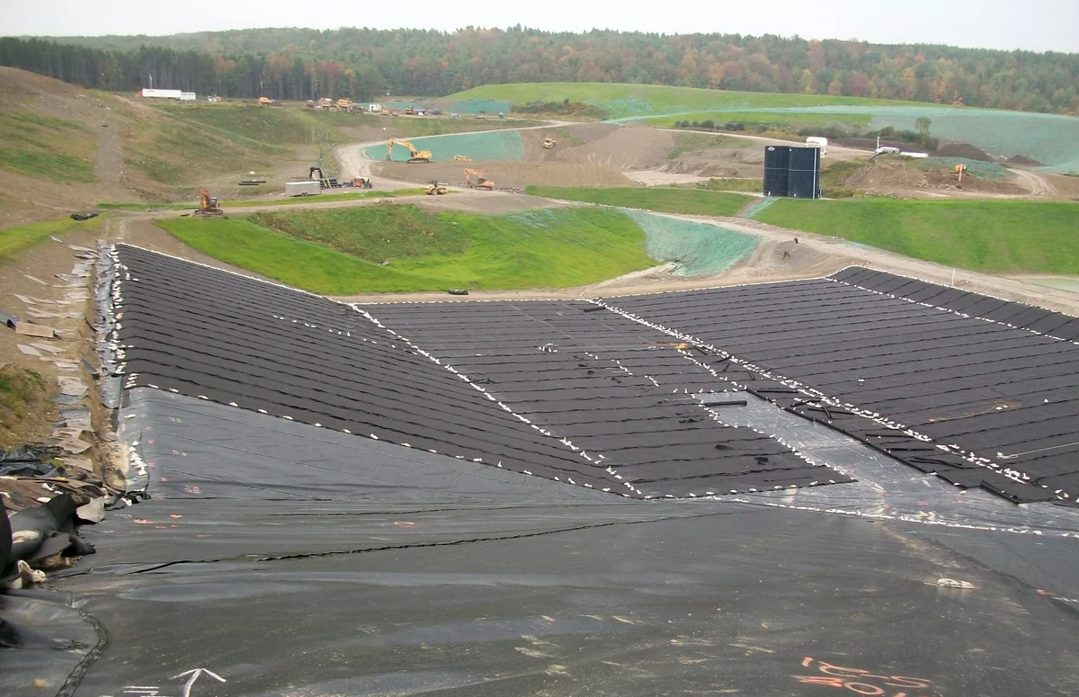 A wide view across extensive landfill earthworks and dark cell lining.