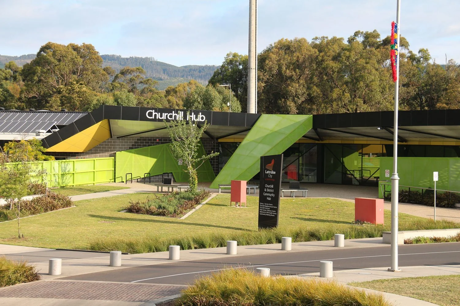 The Churchill Hub building with green and yellow facades, landscaped grounds and entrance paths.